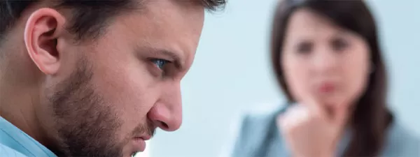 Mann mit Bart schaut konzentriert, Frau im Hintergrund unscharf