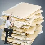 Mann klettert an einem riesigen Stapel übergroßer Aktenordner