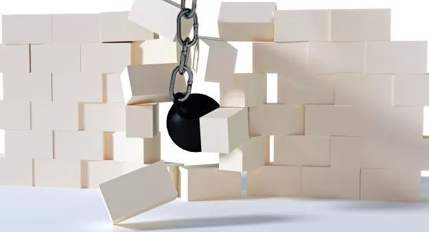 Schwarze Abrissbirne, die eine weiße Ziegelwand durchbricht