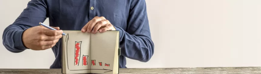 Mann hat ein Buch vor seiner Brust geöffnet und zeichnet darin ein Balkendiagram