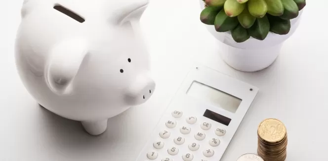 Weißes Sparschwein mit Taschenrechner und Kleingeld