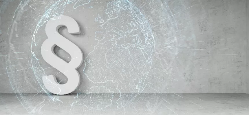 Großes weißes Paragraphenzeichen vor einer Weltkarte als Hintergrund