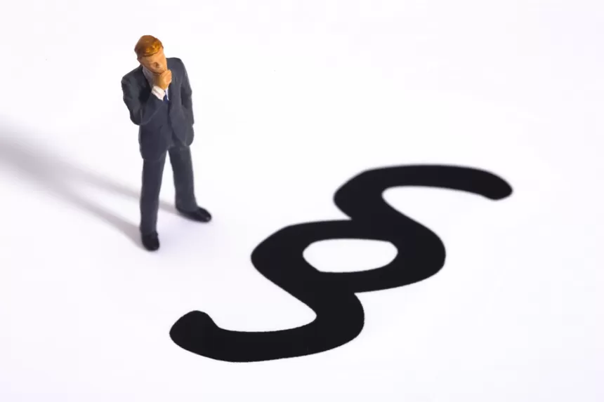 Geschäftsmann steht nachdenklich neben großem Paragraphenzeichen auf weißem Hintergrund