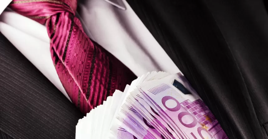 Mann im Anzug mit roter Krawatte hält einen Fächer aus 500-Euro-Scheinen