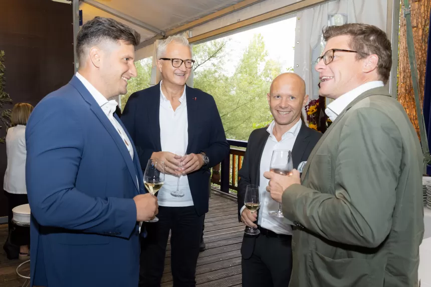 Vier Männer in formeller Kleidung stehen auf einer Terrasse und unterhalten sich bei dem Sommerausklang Event des KSV1870