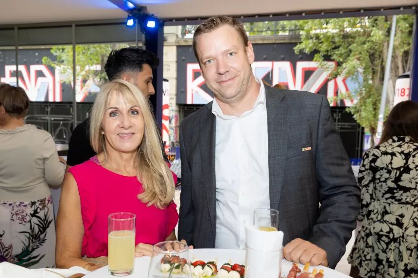 Zwei Personen stehen an einem Stehtisch mit Getränken und kleinen Häppchen bei dem Sommerausklang Event des KSV1870