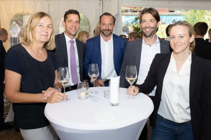 Fünf Personen stehen um einen Stehtisch mit weißen Tischdecke, halten Weingläser beim Sommerausklang des KSV1870