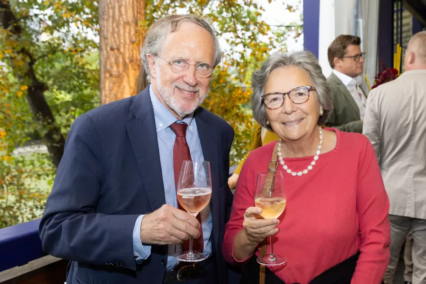 Zwei Personen beim Sommerausklang des KSV1870, sie halten Weingläser mit roséfarbenem Getränk, im Hintergrund weitere Gäste