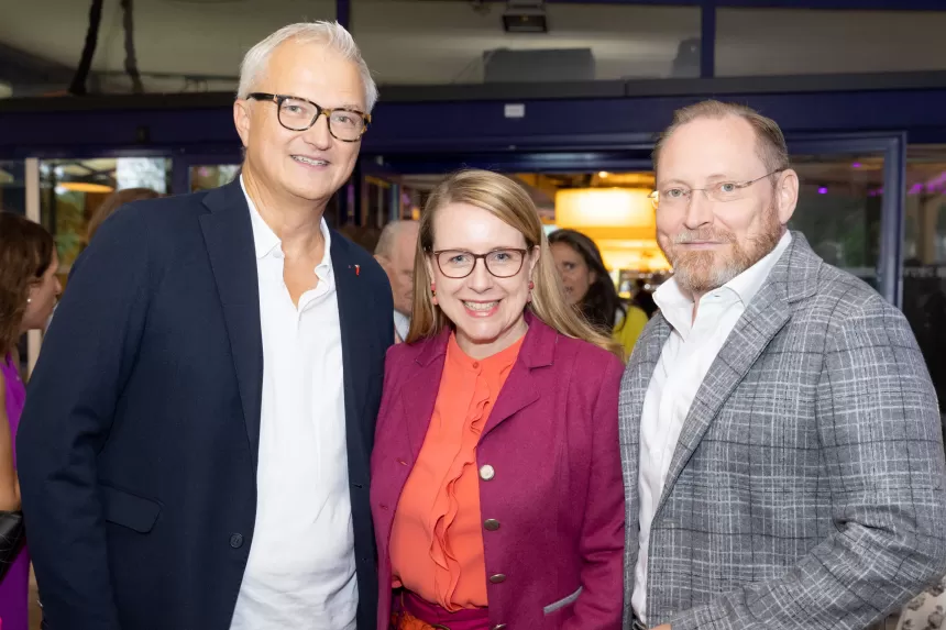 Drei Personen in eleganter Kleidung beim Sommerausklang des KSV1870, stehend in einem Innenraum mit dunklem Hintergrund