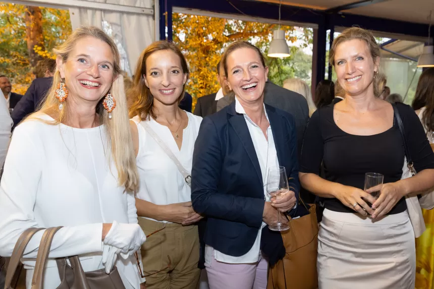 Vier Frauen beim Sommerausklang des KSV1870, stehend in einem hellen Raum mit großen Fenstern, tragen elegante Freizeitkleidung