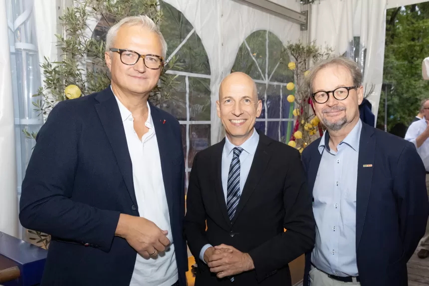 Drei Männer in Anzügen und Hemden stehen zusammen bei Sommerausklang des KSV1870 in einem Zelt mit weißen Vorhängen und Pflanzen im Hintergrund