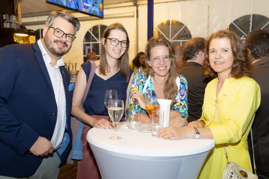 Vier Personen stehen um einen Stehtisch mit Getränken beim Sommerausklang des KSV1870 in einem Zelt mit anderen Gästen im Hintergrund