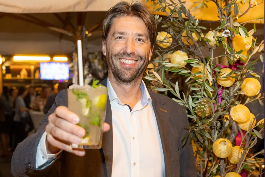 Mann in weißem Hemd und dunklem Sakko hält Cocktailglas mit Limettenscheiben und Minze bei Sommerausklang des KSV1870