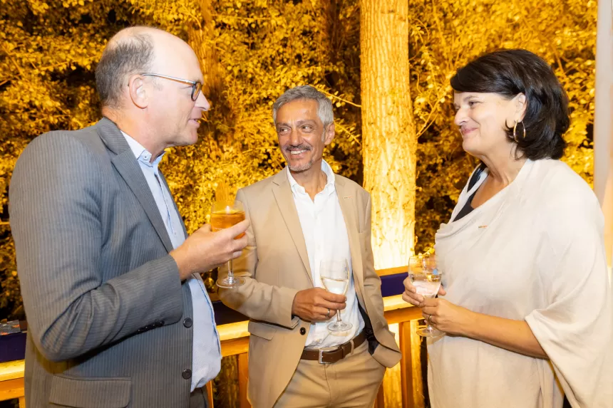 Drei Personen in formeller Kleidung unterhalten sich beim Sommerausklang des KSV1870, zwei Männer und eine Frau mit weißem Oberteil