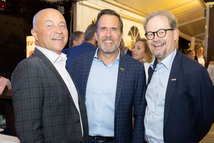 Drei Männer in Anzügen stehen zusammen beim Sommerausklang des KSV1870 in einem festlich beleuchteten Zelt