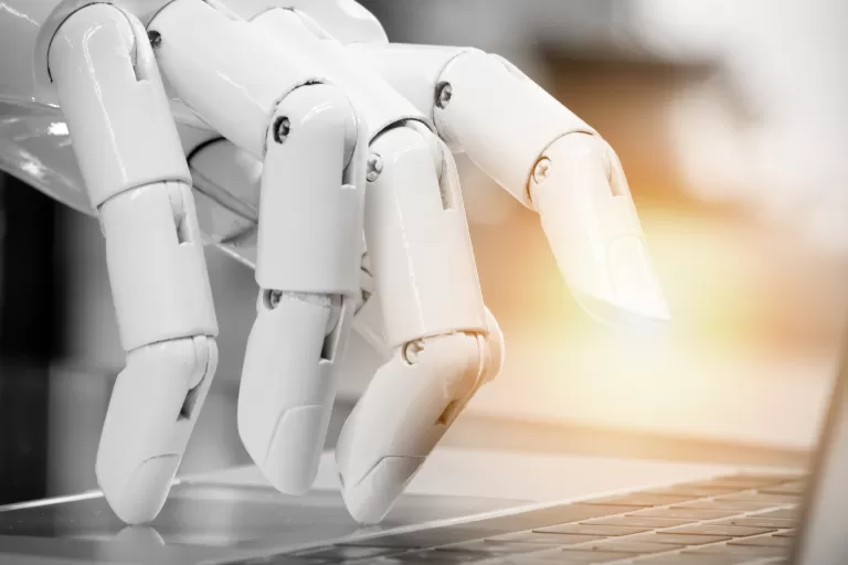 Einer Roboter-Hand tippt auf einem Laptop