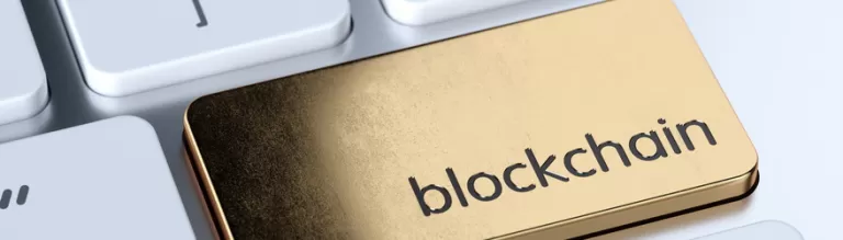 Ein goldener Schlüssel mit der Aufschrift „Blockchain“ liegt auf einer Computertastatur.