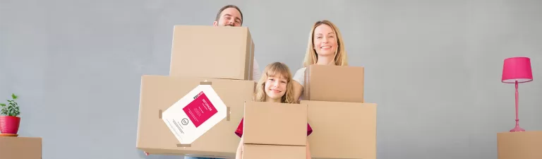 Drei Personen, zwei Erwachsene und ein Kind, stehen hinter großen Pappkartons in einem hellen Raum