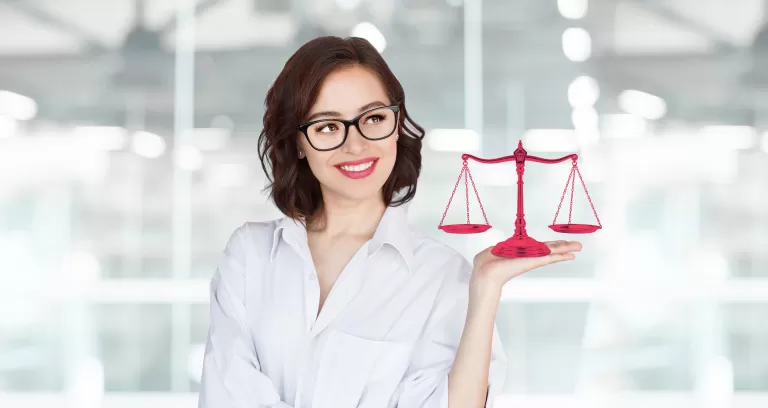 Frau mit Brille hält eine rote Waage in einem modernen Büro