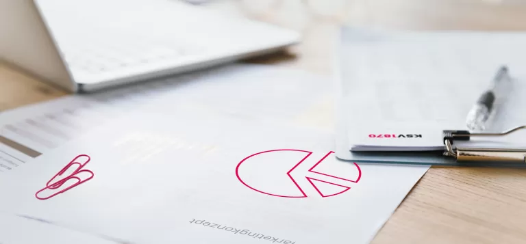 Schreibtisch mit Marketingdaten, darunter ein Diagramm mit Tortendiagramm und Stift