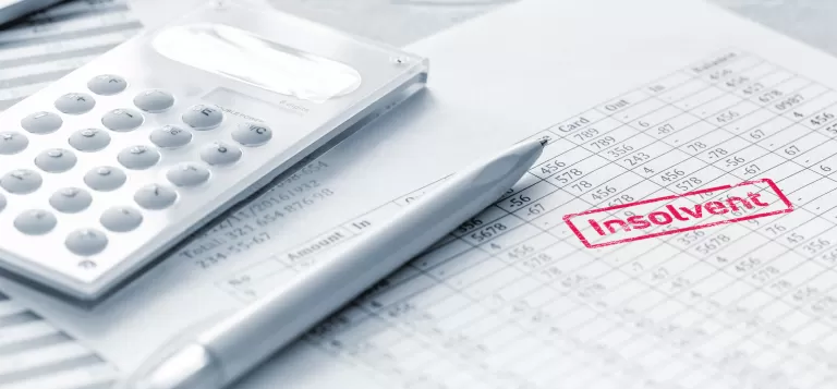 Taschenrechner, Stift und Papier mit rotem Stempel 'insolvent' auf einem Schreibtisch