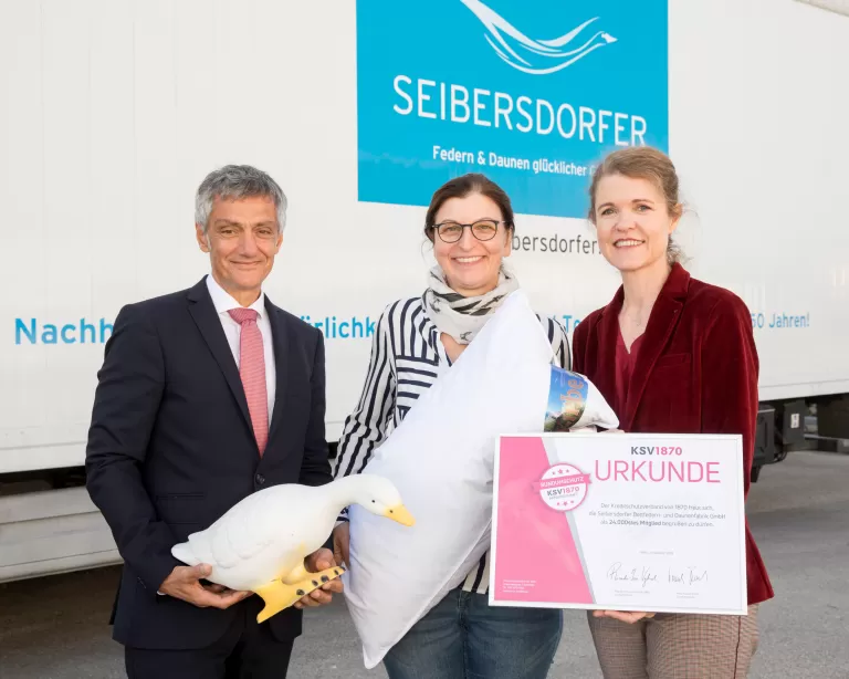 3 Personen stehen vor einem LKW mit der Aufschrift "Seiberdorfer" und ehren das 24.000 Mitglied