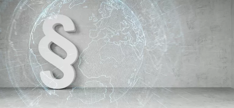 Großes weißes Paragraphenzeichen vor einer Weltkarte als Hintergrund