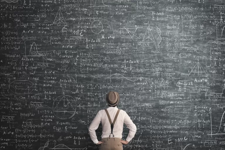 Mann mit Hut und Hosenträgern steht vor einer großen Tafel voller komplexer mathematischer Formeln