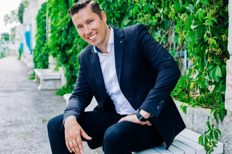 Jürgen Tarbauer sitzt auf einer Bank vor einer mit Efeu bewachsenen Wand