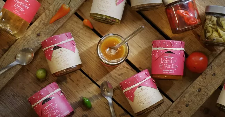 Eine Sammlung von Gläsern mit verschiedenen Lebensmitteln, arrangiert auf einem Holztisch, darunter ist ein Holzboden zu sehen.