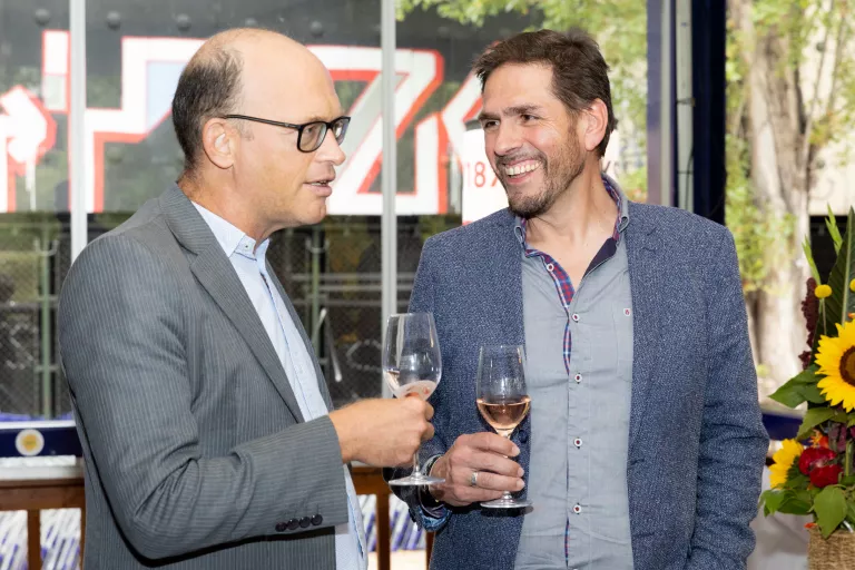 Zwei Männer in Anzügen unterhalten sich bei einem Glas Wein beim Sommerausklang des KSV1870