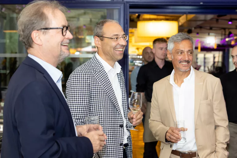 Drei Männer in Anzügen unterhalten sich bei Sommerausklang des KSV1870, halten Getränke in der Hand