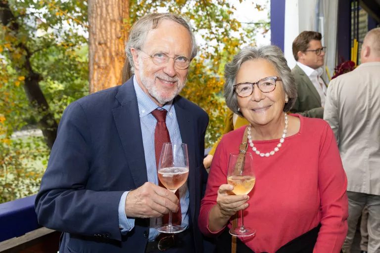 Zwei Personen beim Sommerausklang des KSV1870, sie halten Weingläser mit roséfarbenem Getränk, im Hintergrund weitere Gäste