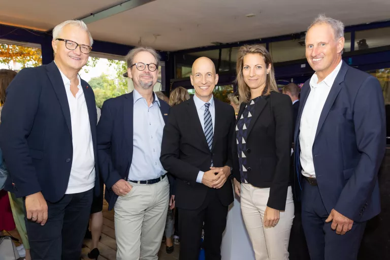 Fünf Personen in Businesskleidung stehen bei Sommerausklang des KSV1870 in einem überdachten Außenbereich