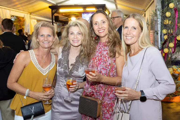 Vier Frauen beim Sommerausklang des KSV1870, stehend und mit Getränken in der Hand, in einem festlich beleuchteten Zelt