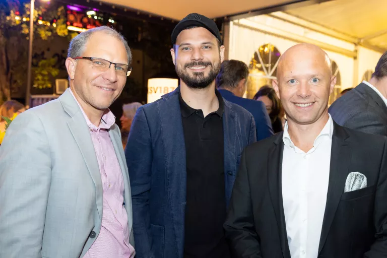 Drei Männer in formeller Kleidung bei KSV1870 Sommerausklang, einer trägt hellgrauen Anzug, einer dunkle Jacke, einer schwarzen Anzug mit weißem Hemd