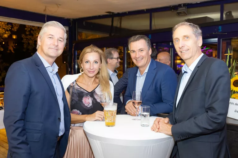 Vier Personen stehen um einen Stehtisch mit Getränken beim Sommerausklang des KSV1870 in einem Zelt mit anderen Gästen im Hintergrund