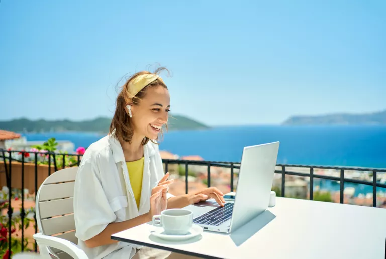 Frau mit Laptop am Balkon
