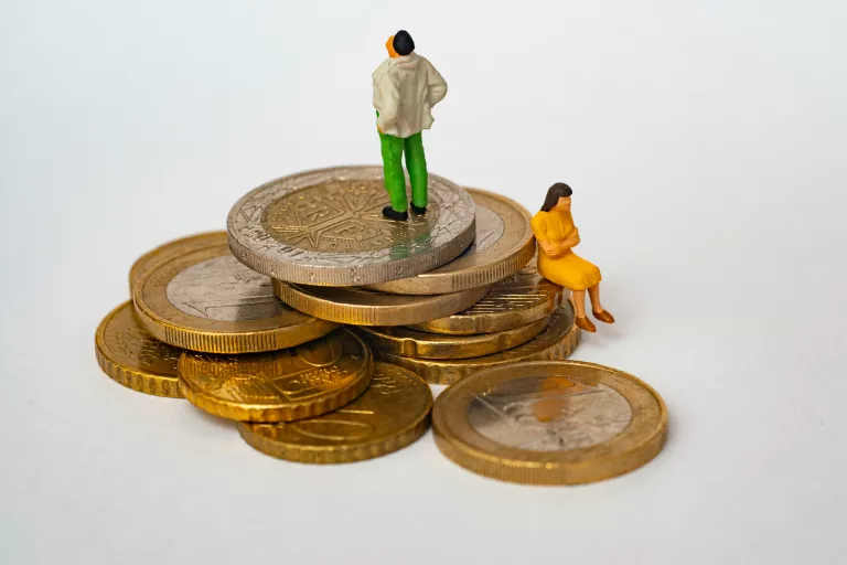kleine Menschenfiguren sitzen auf Euromünzen