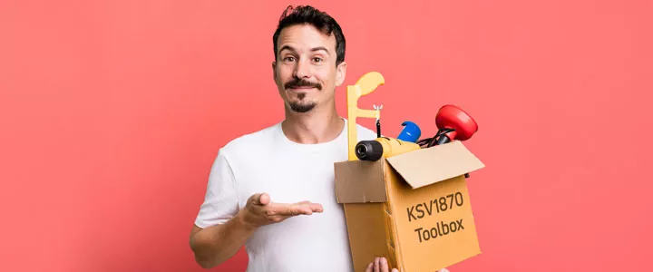 Mann in weißem T-Shirt und mit Bart. Er hat eine Kiste mit Werkzeugen in der linken Hand hat. Auf der Kiste steht "KSV1870 Toolbox". Er deutet mit der rehcten Hand auf die Kiste und lächelt. Der Hintergrund ist rosa. 