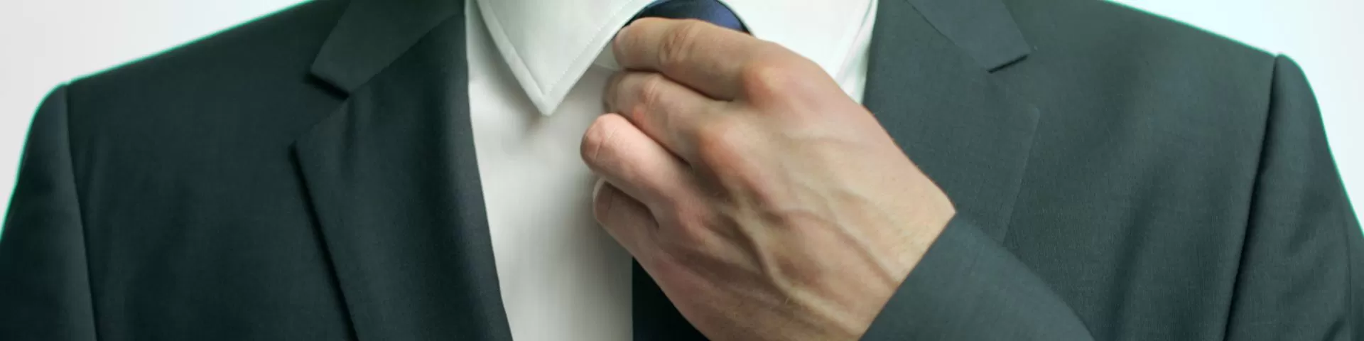 Mann im Anzug richtet seine Krawatte