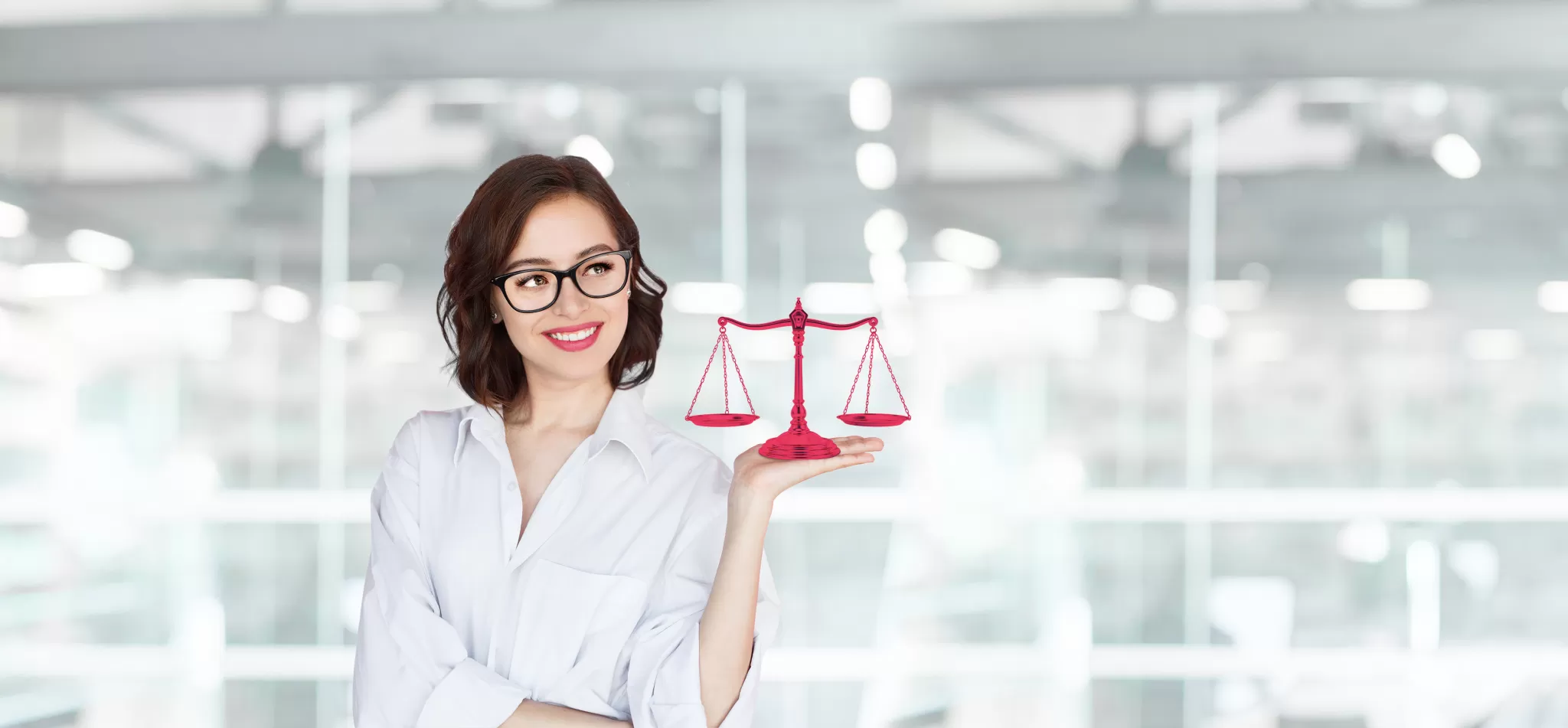 Frau mit Brille hält eine rote Waage in einem modernen Büro