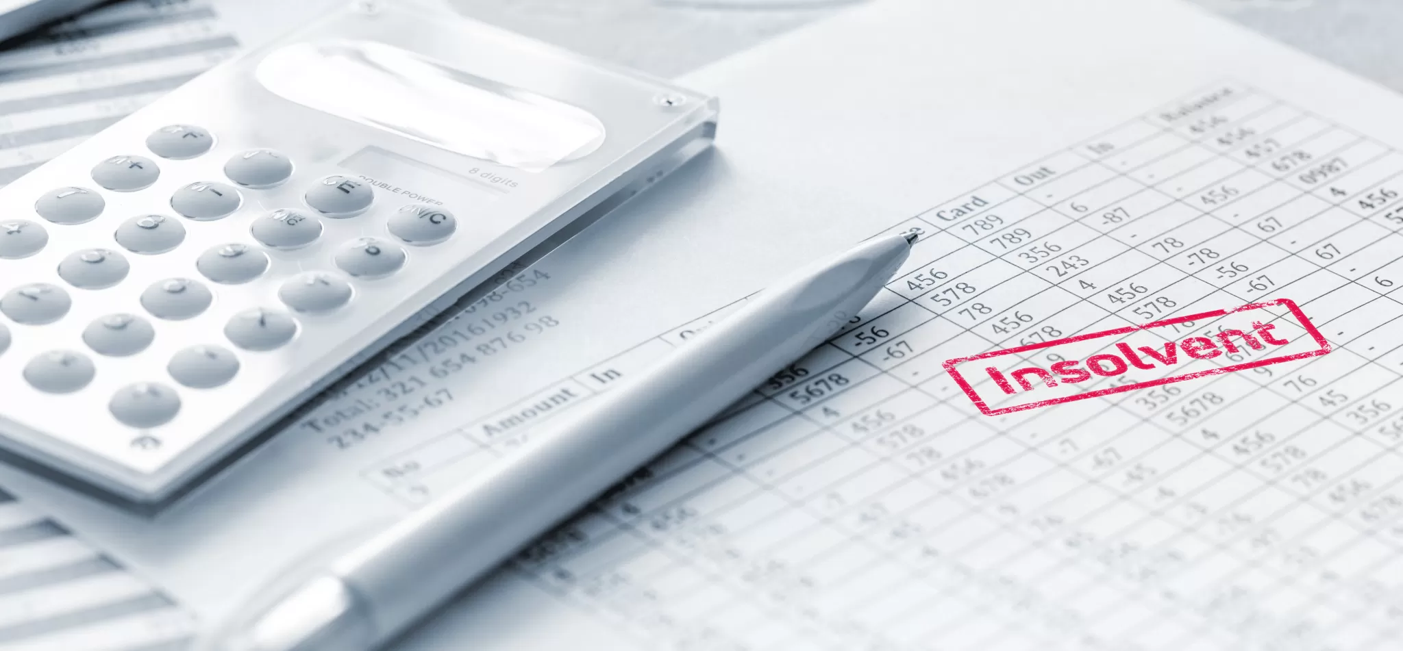 Taschenrechner, Stift und Papier mit rotem Stempel 'insolvent' auf einem Schreibtisch