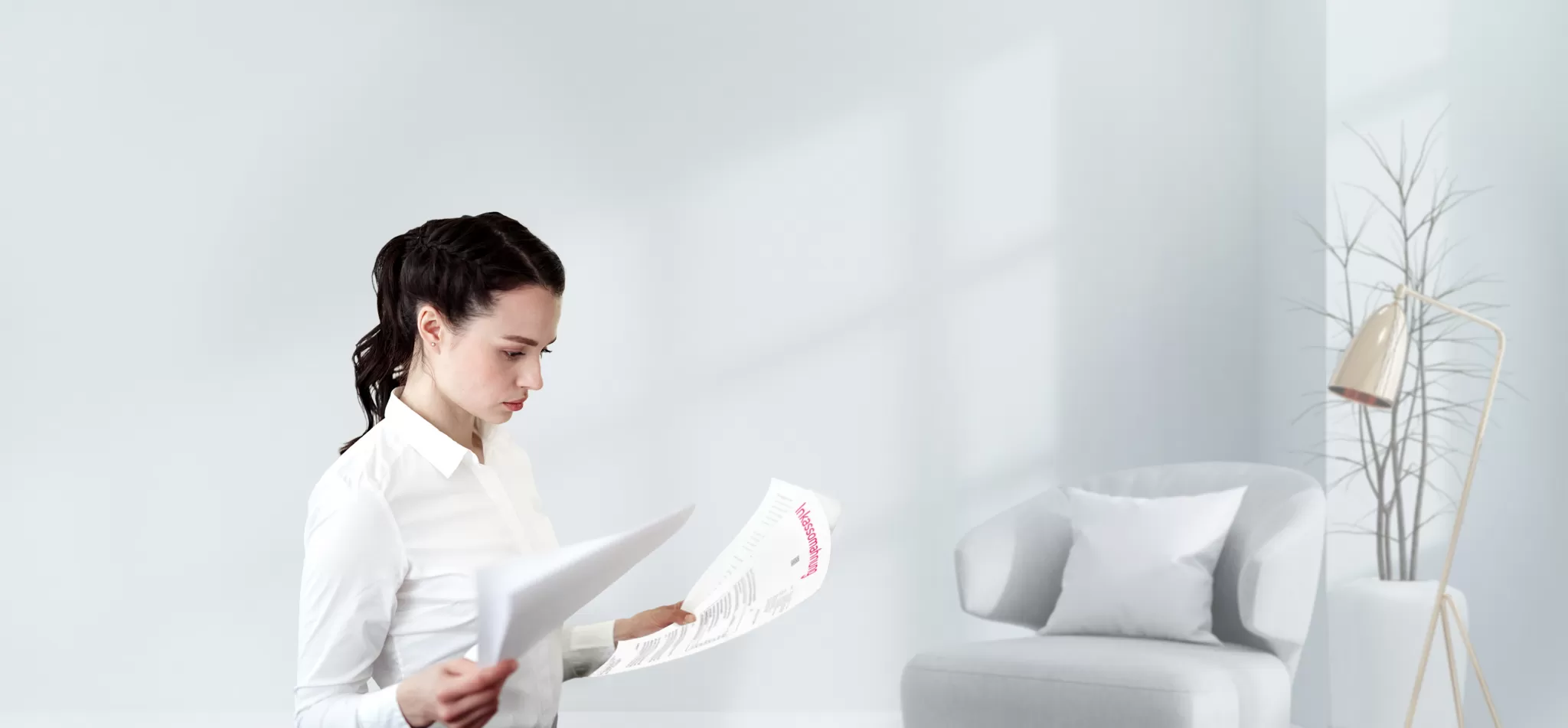 Frau in weißem Hemd liest konzentriert Dokument in hellem, minimalistischem Wohnzimmer